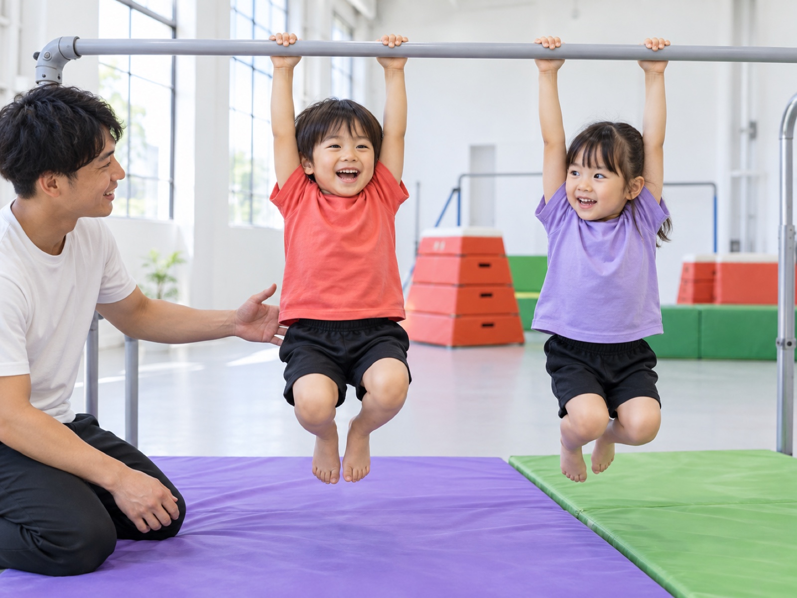 鉄棒にぶら下がる2人と、しゃがんで支える先生
